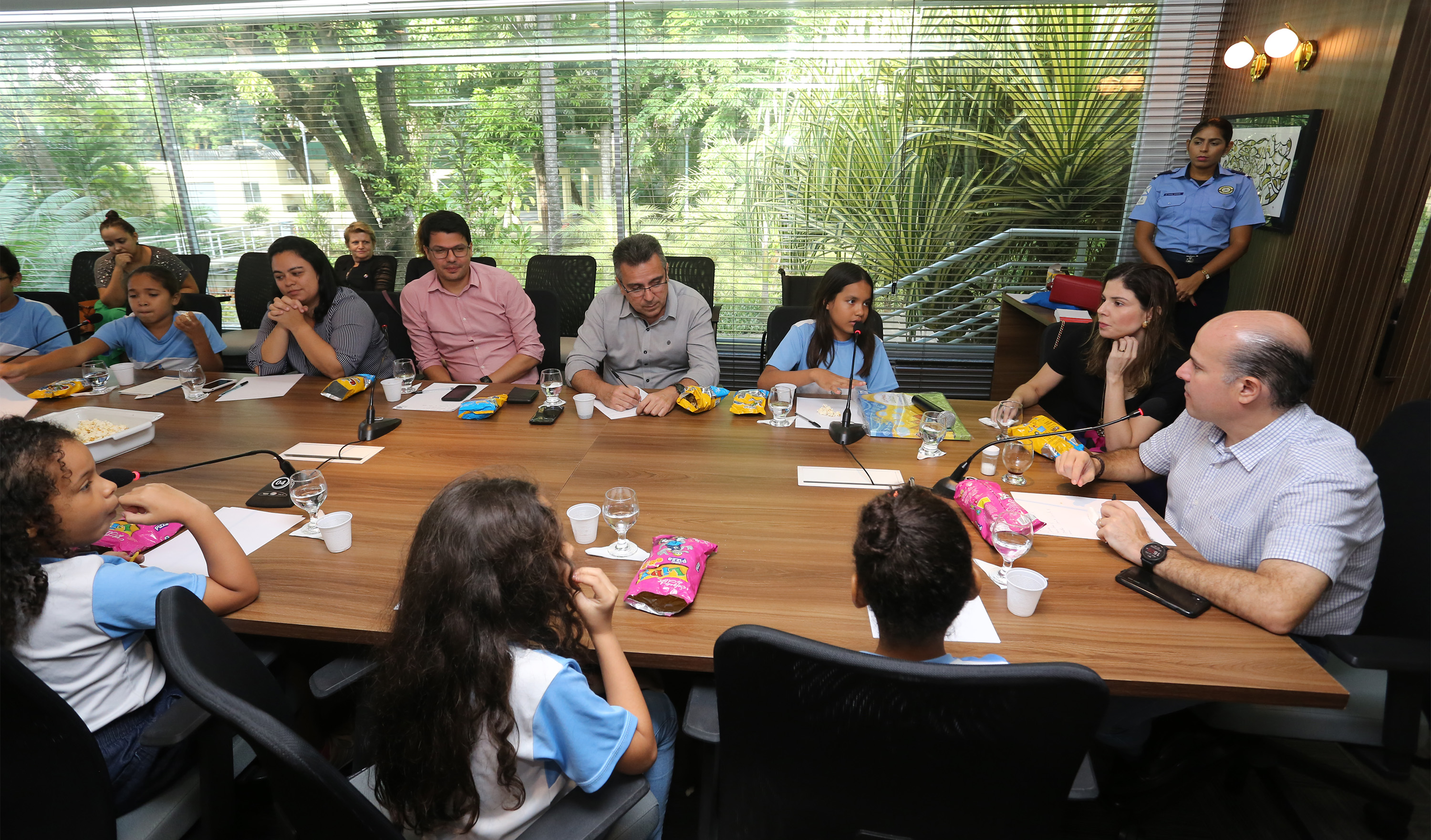 prefeito e primeira-dama sentados à mesa conversando com pessoas e crianças sentados ao redor